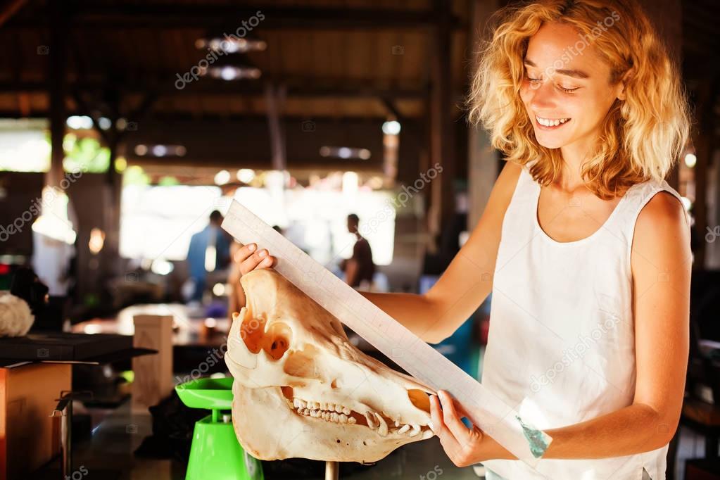 female paleontologist examining a skull of wild boar