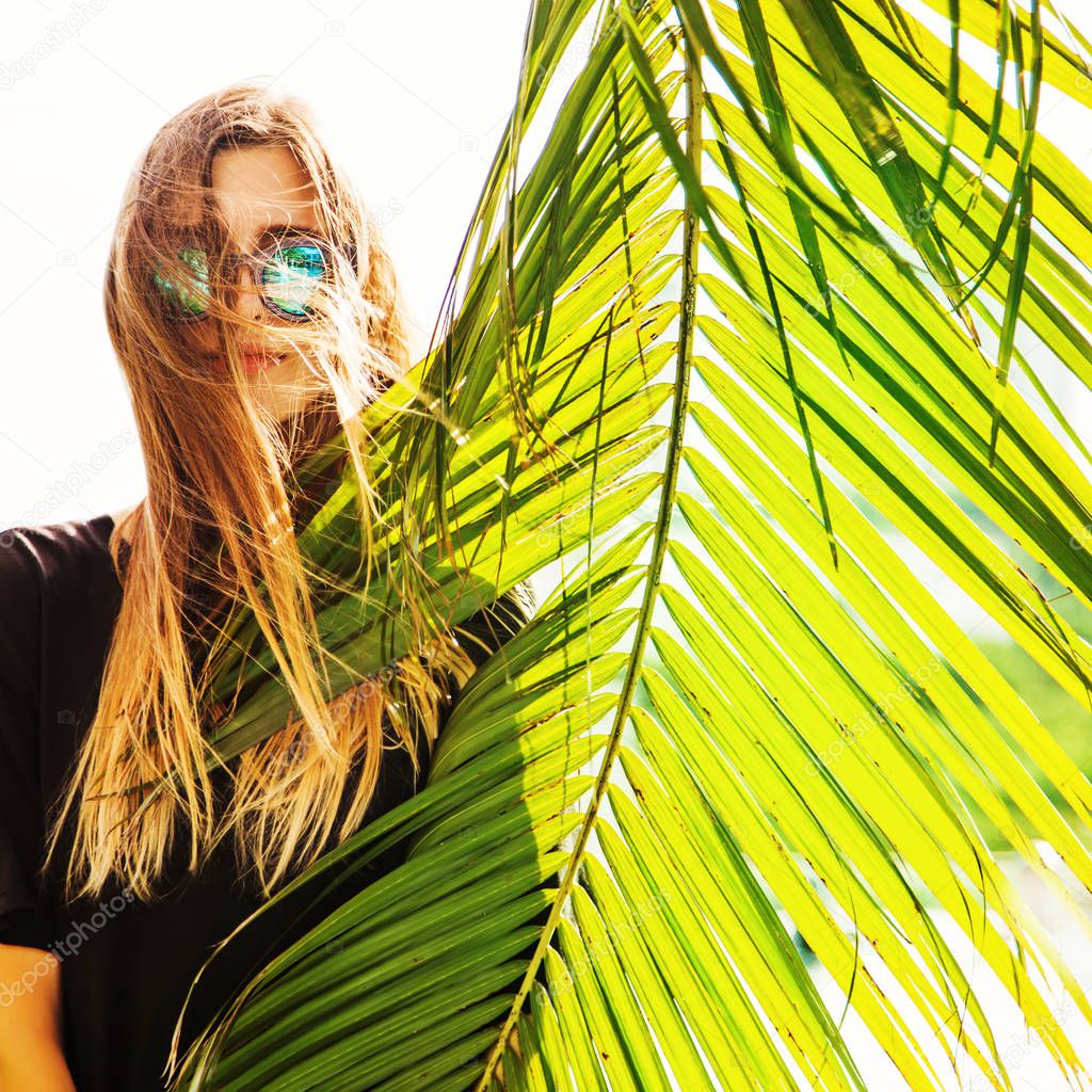 woman wearing sunglasses posing with palm trees