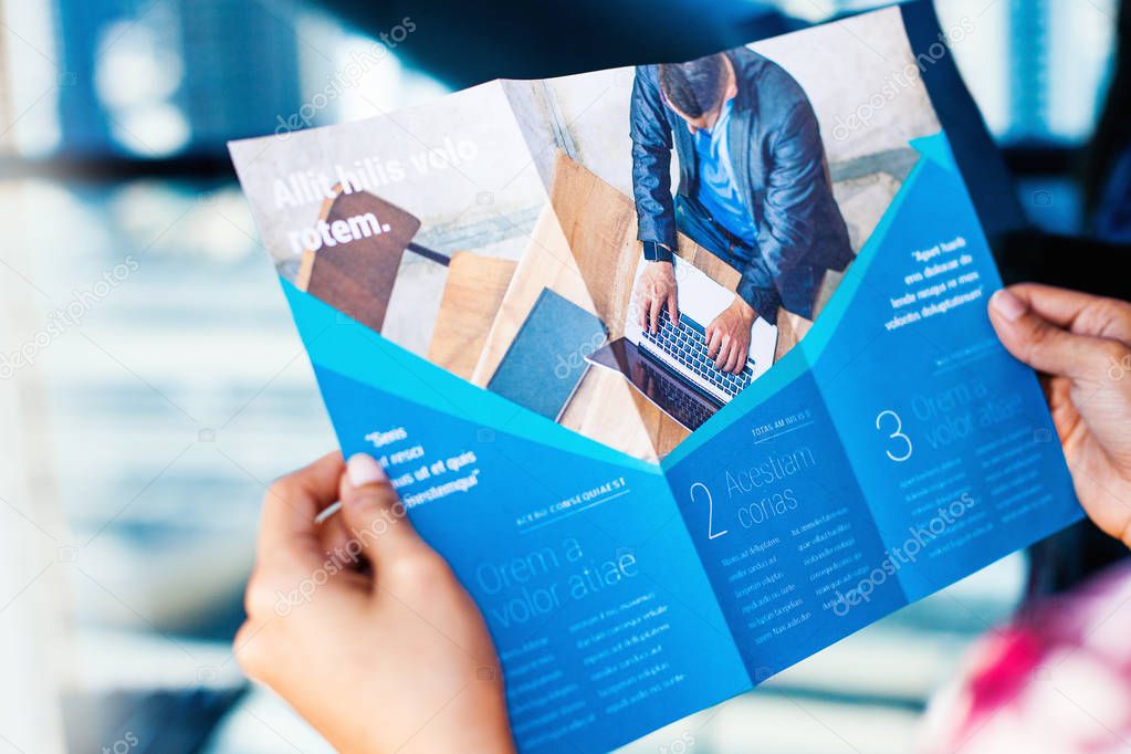 Hands holding a business brochure, close up
