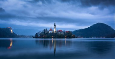 02 Kasım 2019, Bled Lake (Slovenya): Bulutlu bir günde şafak vakti, ön planda Mary 'nin Varsayımı Adası, arka planda dağlar ve Kanlı Kale