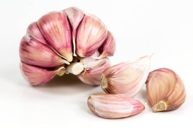 Açılmış yarı soyulmuş organik sarımsak ampulü ve karanfil beyaz arka planda izole edilmiş.