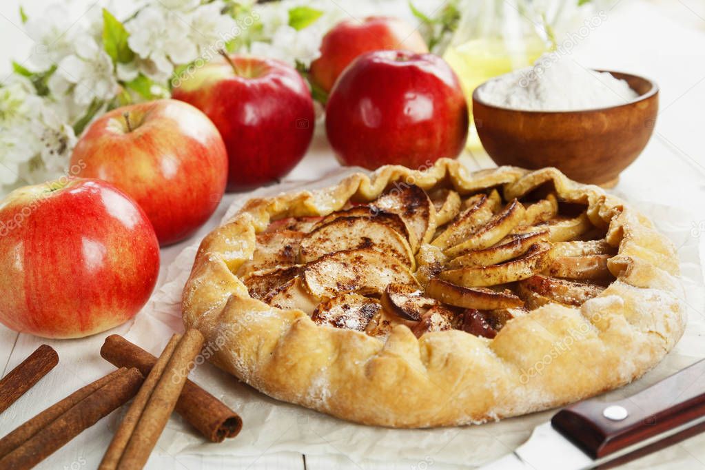 Baked galette or open pie with apples and cinnamon on the table
