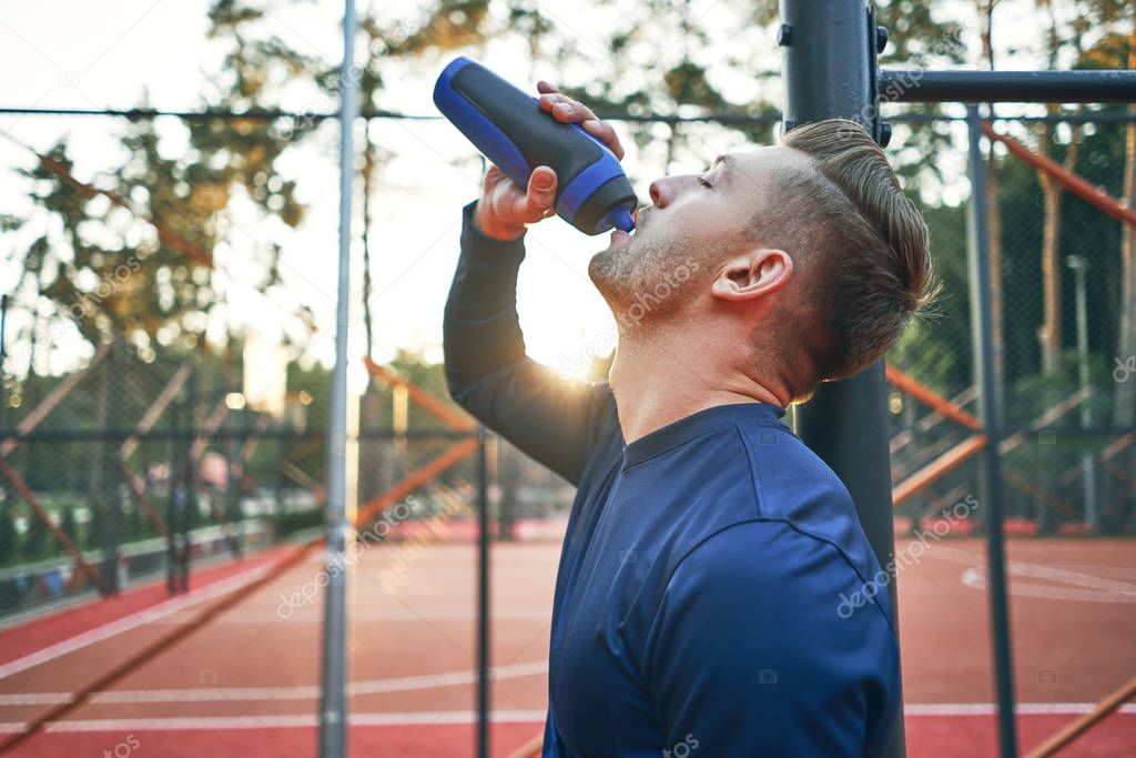 guy drinks water after training 