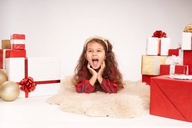 Küçük kız yeni yıl hediyeleriyle çevrili.