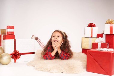 Küçük kız yeni yıl hediyeleriyle çevrili.