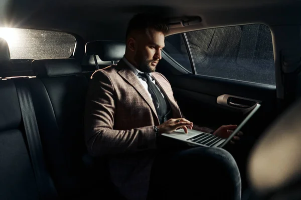 guy in car with laptop and phone