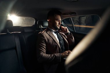 Dizüstü bilgisayarı ve telefonu olan bir adam.