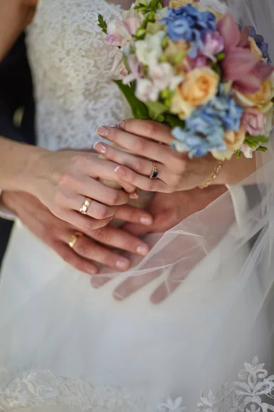 Brudgummen kramar bruden som håller en bröllopsbukett — Stockfoto