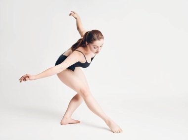 Esmer kız beyaz arka planda bale unsurları gösteriyor.