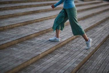 girl in white sneakers and pants walking on the stairs