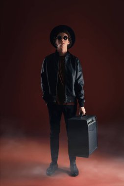 Gözlüklü genç bir adam ve stüdyoda müzik köşesi olan bir şapka. 