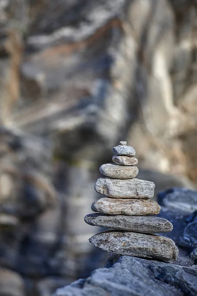 Pyramide de diverses pierres sur un fond de roche — Photo