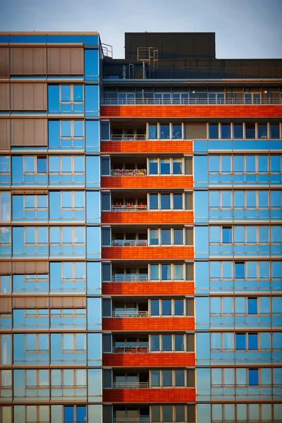 Mavi gökyüzüne karşı turuncu balkonlu çok katlı bir bina. Stok Fotoğraf