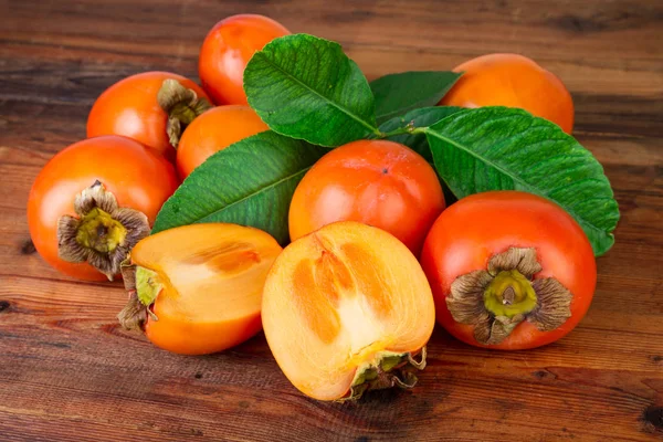 Ripe persimmons kaki fruits on rustic background — Stock Photo, Image