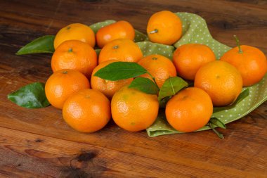 koyu ahşap masa üzerinde yeşil peçete ile mandalina