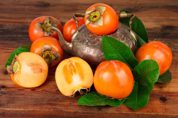 Frutas maduras de caqui con maceta de té vintage . — Foto de Stock