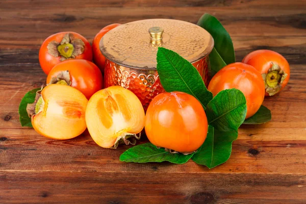 Persimmons with copper vase on old wood Oriental East still life — Stock Photo, Image