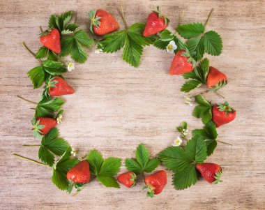 Çilekli çerçeve. Ahşap arka plan üzerinde yaprakları ile taze çilek