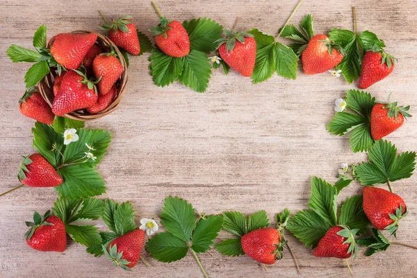 Strawberries creative arrangement over light wooden background. Top view, copy space