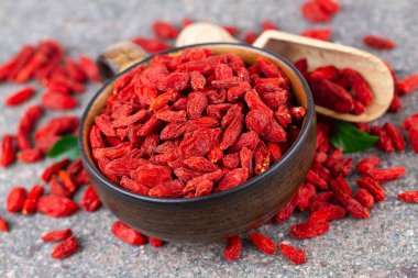 Gri taşlı arka planda kırmızı goji üzümü olan bir fincan. Seçici odak, yukarıdaki görünüm