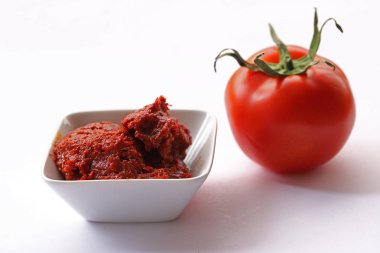 Beyaz arka planda domates ve kâseye domates ezmesi..