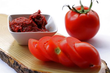 Beyaz arka planda domates ve kâseye domates ezmesi..