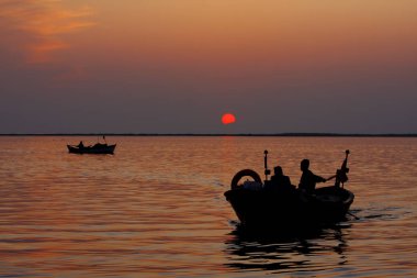 Fishing boats returning from fish in the sea at sunset.