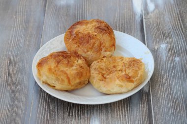 Three izmir boyoz in white plate on wooden background
