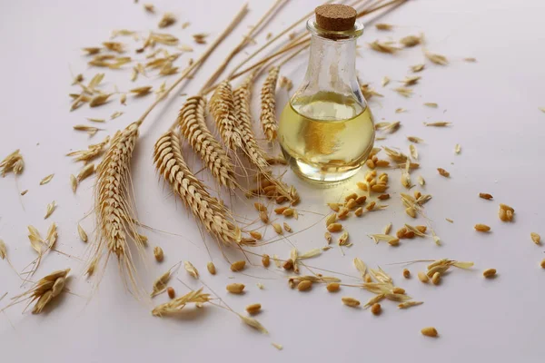 Beyaz zeminde buğday kafalar ve şişede buğday yağı