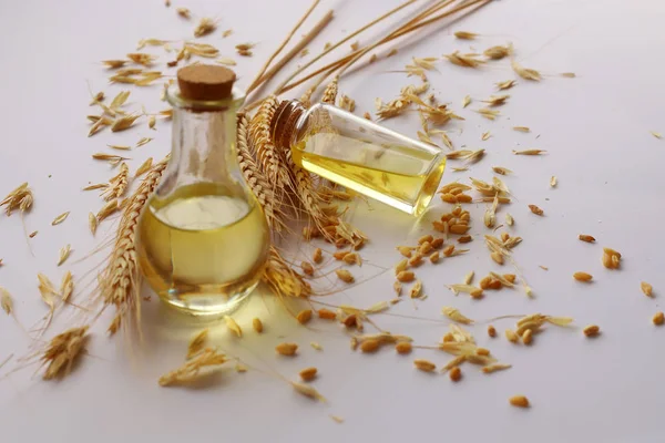 Beyaz zeminde buğday kafalar ve şişede buğday yağı