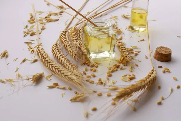 Beyaz zeminde buğday kafalar ve şişede buğday yağı
