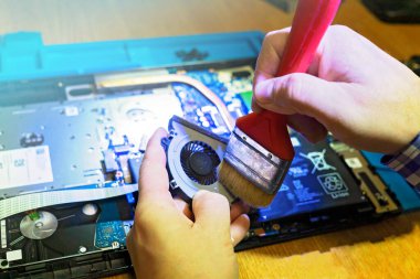 Mühendis laptop soğutucusunun mekanik temizliğini yapıyor.