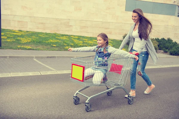 Mother pushes her daughter in  cart — Stock Photo, Image