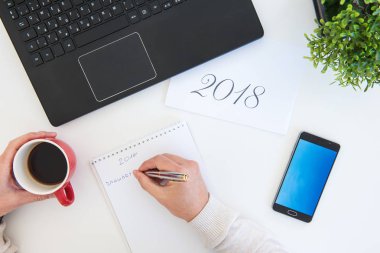 Öğelerin en iyi görünümü office iş istasyonunda bir masada. Düz ile 2018 italik başlık ve not defterinde yazılı elle yatıyordu.