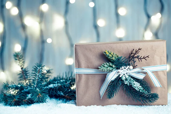 Kerstmis achtergrond met versieringen en geschenkdozen op een houten bord met sneeuw, takken van een kerstboom en een bokeh van een lichtgevende garland — Stockfoto