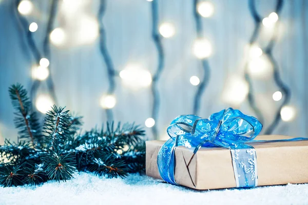Kerstmis achtergrond met versieringen en geschenkdozen op een houten bord met sneeuw, takken van een kerstboom en een bokeh van een lichtgevende garland — Stockfoto