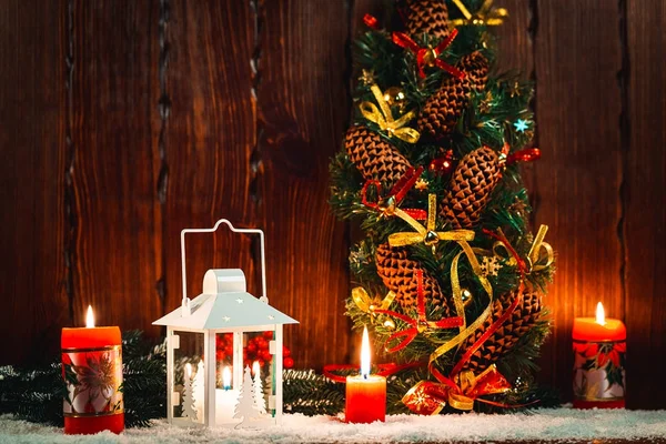 Christmas and New Year background with Christmas candle lantern and Christmas tree branches, snow and decorations, wooden wall behind. Free space — Stock Photo, Image