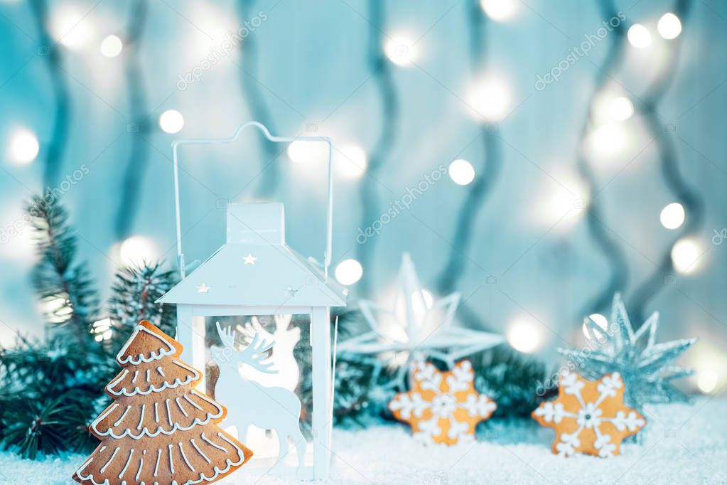 Christmas candle lantern and Christmas tree branches, snow, gingerbread, snowflakes and decorations on bokeh background blurred lights. Free space