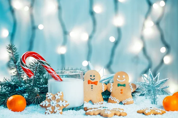 Pão de gengibre de Natal e leite com decorações, neve, ramos de árvore de Natal no fundo luzes borradas bokeh. Espaço livre — Fotografia de Stock