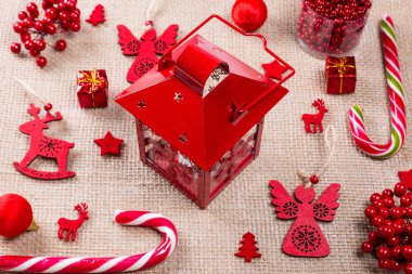 Kırmızı oyuncaklar, şeker, hediyeler, fener ve çuval bezi üzerinde yeni yıl süslemeleri Noel arka plan yaptı. Yat, görünümü, kopya alanı top. Neşeli Noel kartı