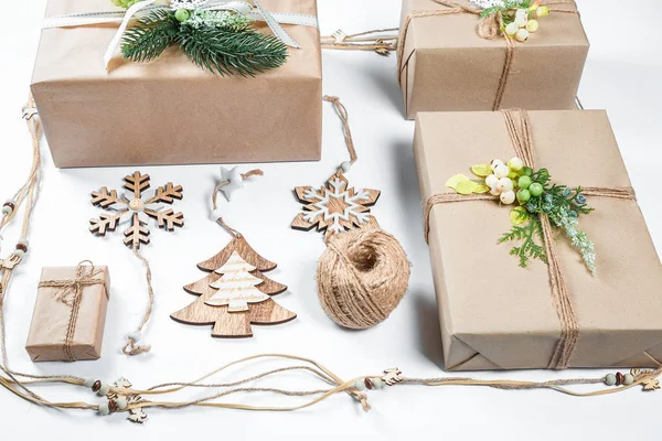 Classy Kerstmis geschenken vak presenteert in bruin papier met speelgoed en Nieuwjaar decor op wit. Merry Xmas card achtergrond — Stockfoto
