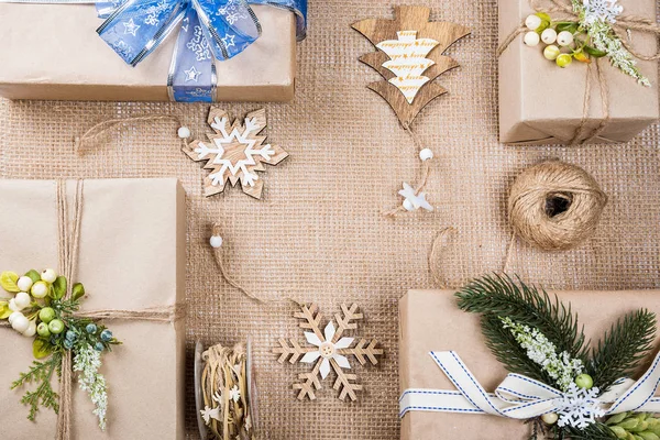 Classy Kerstmis geschenken vak presenteert in bruin papier met speelgoed en Nieuwjaar decor op jute. Merry Xmas card achtergrond — Stockfoto