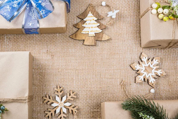 Classy Kerstmis geschenken vak presenteert in bruin papier met speelgoed en Nieuwjaar decor op jute. Merry Xmas card achtergrond — Stockfoto
