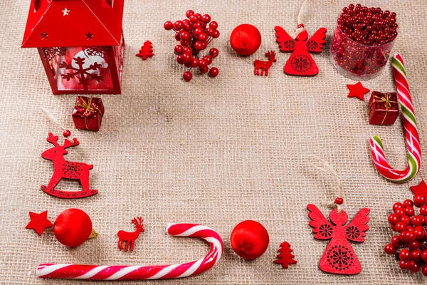 Рождественская рамка из красных игрушек, конфет, подарков, фонарей и новогодних украшений на мешковине. Плоская лежала, вид сверху, копировальное пространство. Весёлого рождественского фона — стоковое фото