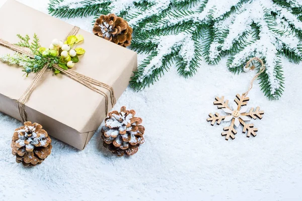 Cadre de Noël avec cadeau, les branches de l'arbre de Noël et des décorations en bois sur fond de neige. Composition de Noël simple avec espace libre — Photo
