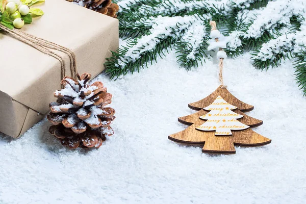 Kerst frame met gift, de takken van de kerstboom en houten decoraties op sneeuw achtergrond. Eenvoudige Kerstmis samenstelling met vrije ruimte — Stockfoto