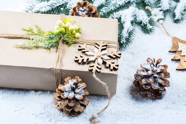 Kerst frame met gift, de takken van de kerstboom en houten decoraties op sneeuw achtergrond. Eenvoudige Kerstmis samenstelling met vrije ruimte — Stockfoto