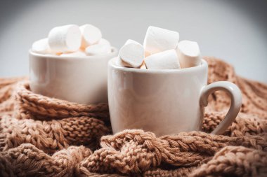 Kakao veya marshmallow bir kahverengi örme kış eşarp ile beyaz bir fincan kahveyle. Güzel Noel arka plan