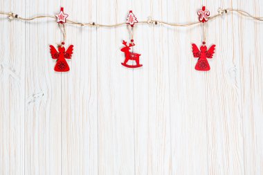 Noel bir geyik ve Beyaz ahşap zemin üzerinde bir melek ip şeklinde ahşap kırmızı oyuncaklar. Güzel bayram tebrik kartı boş alan ile