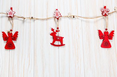 Noel bir geyik ve Beyaz ahşap zemin üzerinde bir melek ip şeklinde ahşap kırmızı oyuncaklar. Güzel bayram tebrik kartı boş alan ile